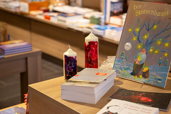Zwei Kerzen neben Büchern auf dem Sternentisch