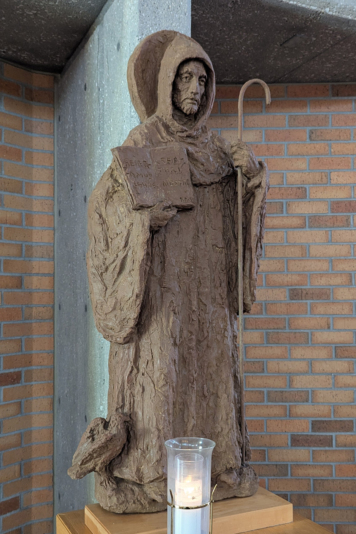 Figur vom heiligen Benedikt mit Kerze zu seinen Füßen