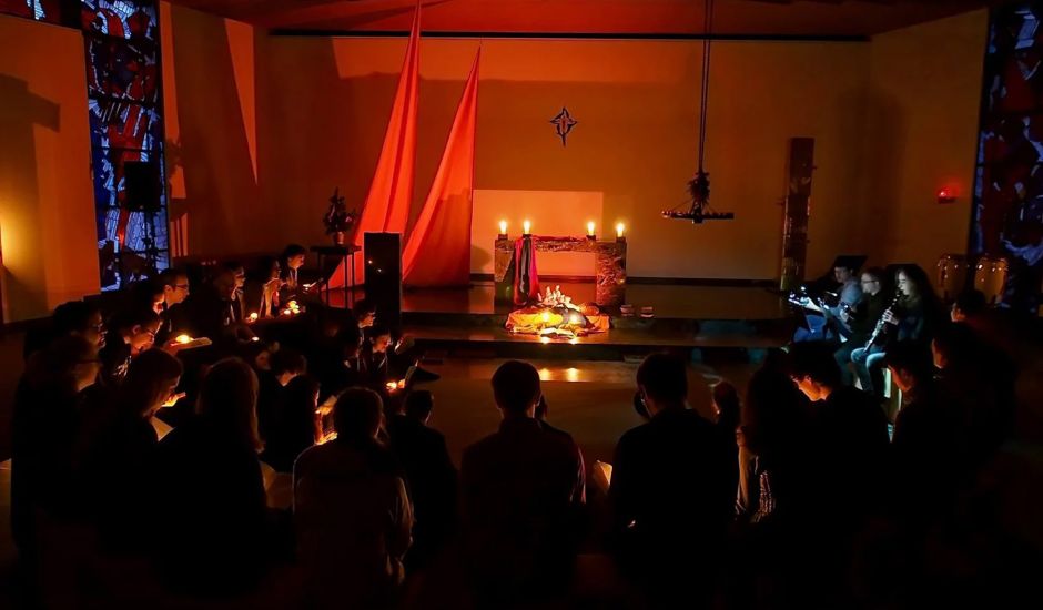 Junge Menschen feiern Andacht in einer mit Kerzen beleuchtenden Kapelle