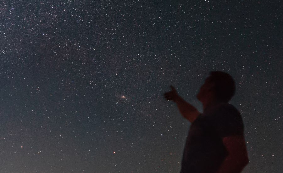 Mann zeigt auf den Sternenhimmel